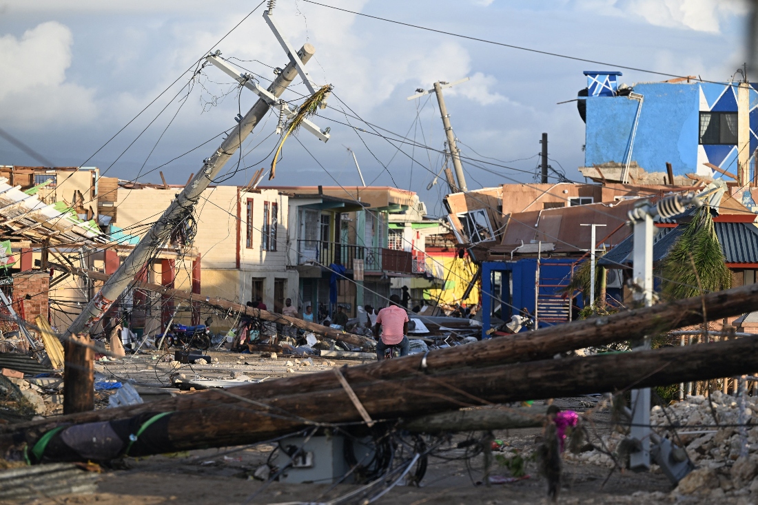 Electrical poles are down as a man bikes through the destroyed neighborood of North Street following the passage of Hurricane Melissa, in Black River, Jamaica. (AFP)