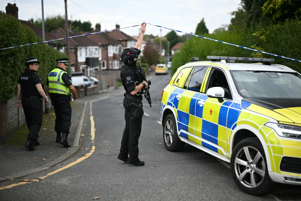 An armed Police officer lifts a cordon for a police car to be driven away from White House Avenue, near the Heaton Park Hebrew Congregation synagogue in Crumpsall, north Manchester, Oct. 2, 2025. (AFP)