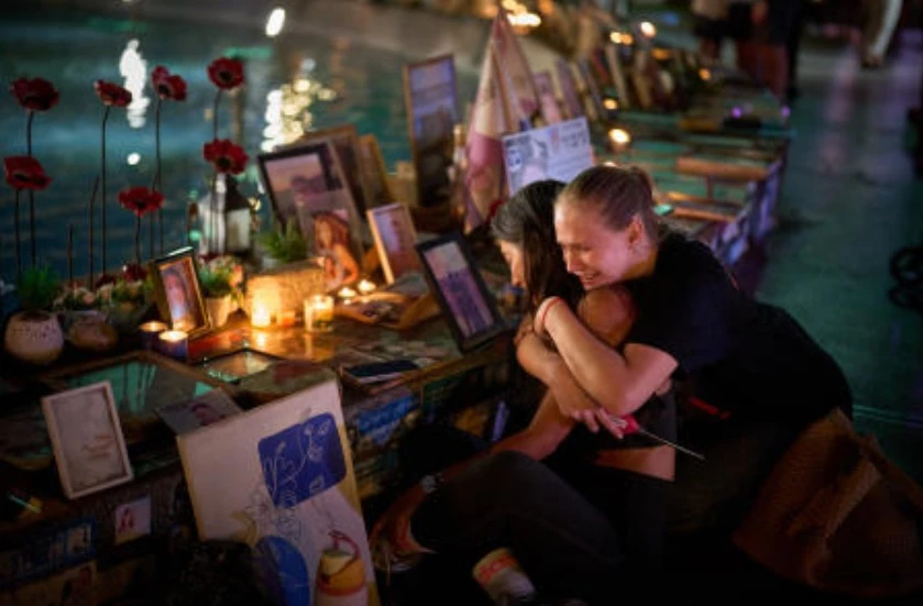 Yuval Miranda and Katya Emelianova cry as they embrace next to the photographs of Israelis who were killed in the deadly Oct. 7, 2023 Hamas attack on Israel, at a memorial marking the 2nd anniversary of the assault, in Tel Aviv, Oct. 7, 2025. (AP)
