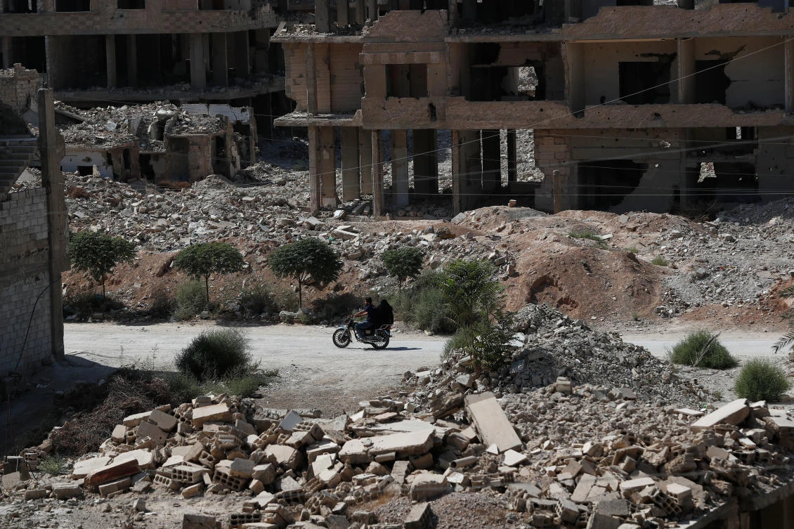 A couple rides a motorcycle past destroyed buildings in Ein Tarma, Monday, Oct. 6, 2025, a suburb of Damascus that was heavily bombed by forces loyal to Syrian President Bashar Assad during the war in Syria. (AP)