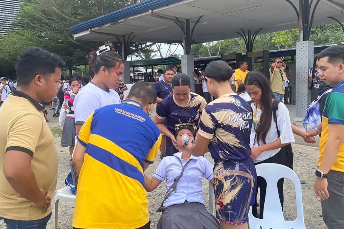 This handout photo from Golden Cornucopia - Davao de Oro State College taken and received on October 10, 2025, shows students helping a fellow student as they gather outside the school buildings after an earthquake in Davao de Oro, Mindanao. (Handout photo via AFP)