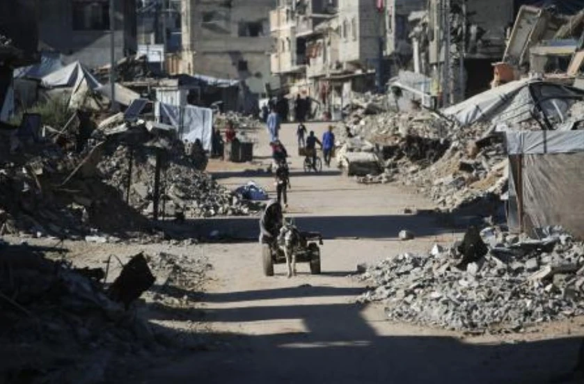 A man rides a donkey cart past destroyed buildings as displaced Palestinians return to their homes in the in Al-Zahra area, north of the Nuseirat refugee camp in the central Gaza Strip, on Oct. 14, 2025, a day after a ceasefire came into effect. (AFP)