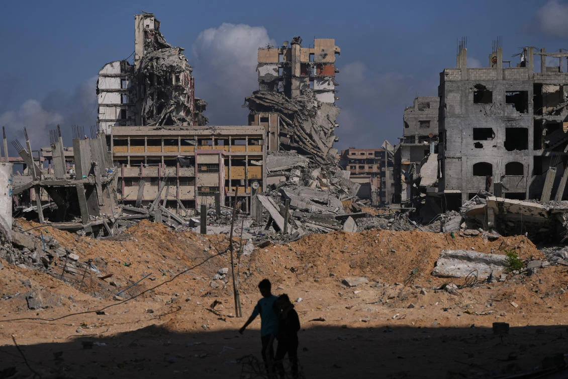 Palestinians walk through the destruction caused by the Israeli air and ground offensive in the Al-Shati camp, Gaza City, on Friday. (AP)