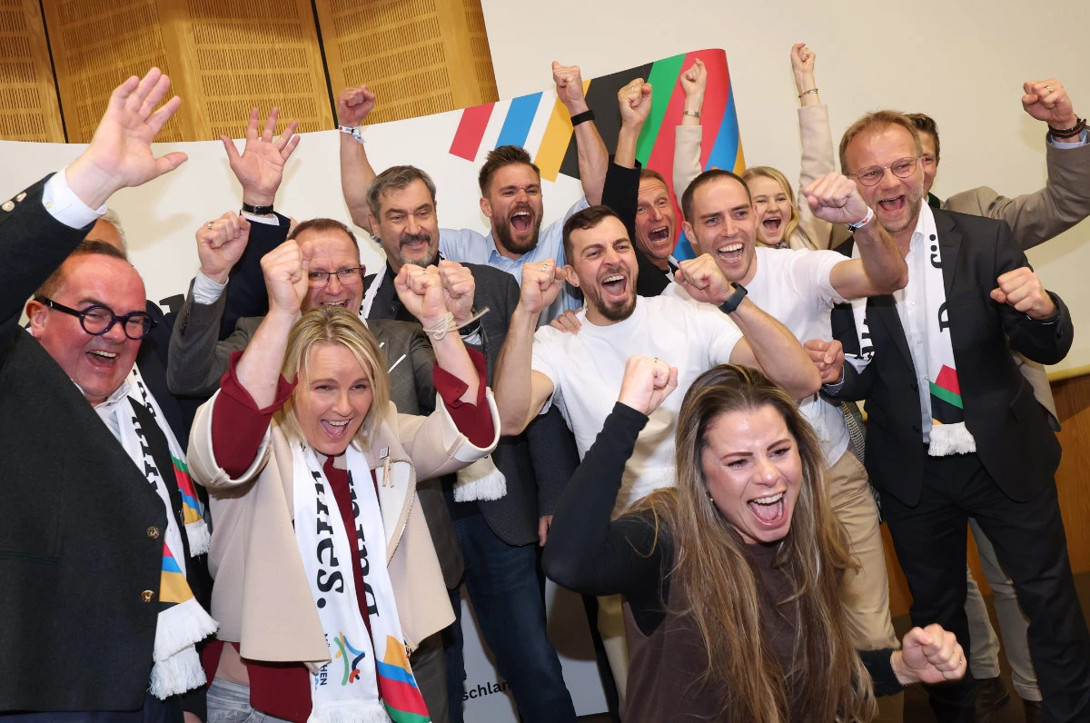 Athletes, politicians and officials react after the announcement of the first projections on the result of the referendum on the city's Olympic bid at the Haus des Sports in Munich on Oct. 26, 2025. (dpa via AP)