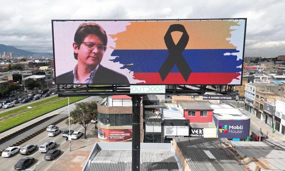 Above, a banner with an image of slain Colombian presidential candidate Miguel Uribe and a Colombian national flag bearing a black ribbon in Bogota on Aug. 12, 2025. (AFP)