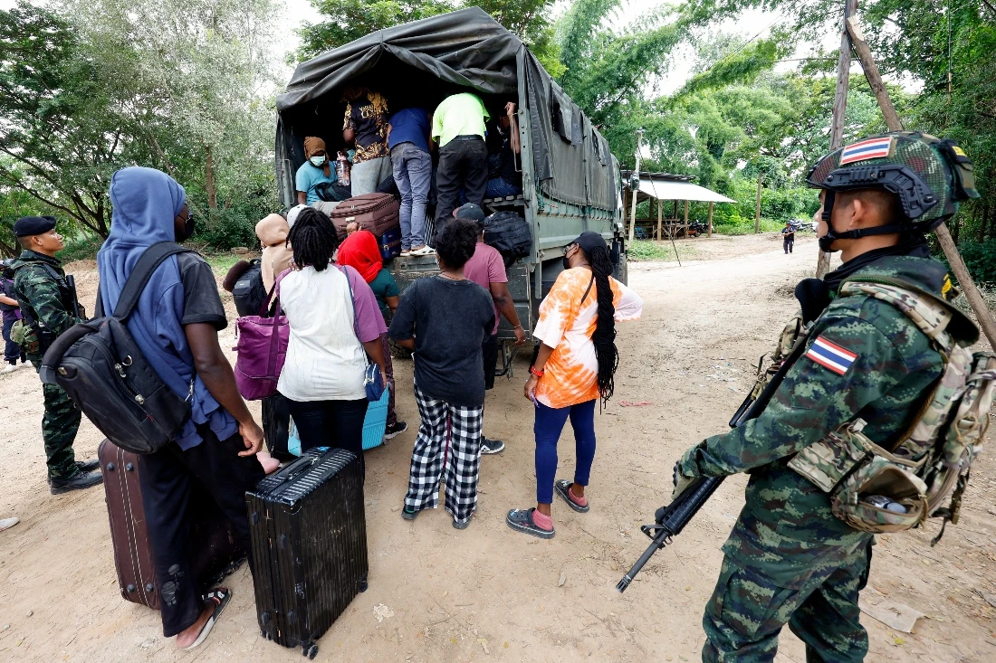 People from various countries, who were working in the KK Park compound in Myanmar and crossed to Thailand via the Moei river, board a vehicle as Thai soldiers keep watch in Mae Sot District, Tak Province. (AFP)