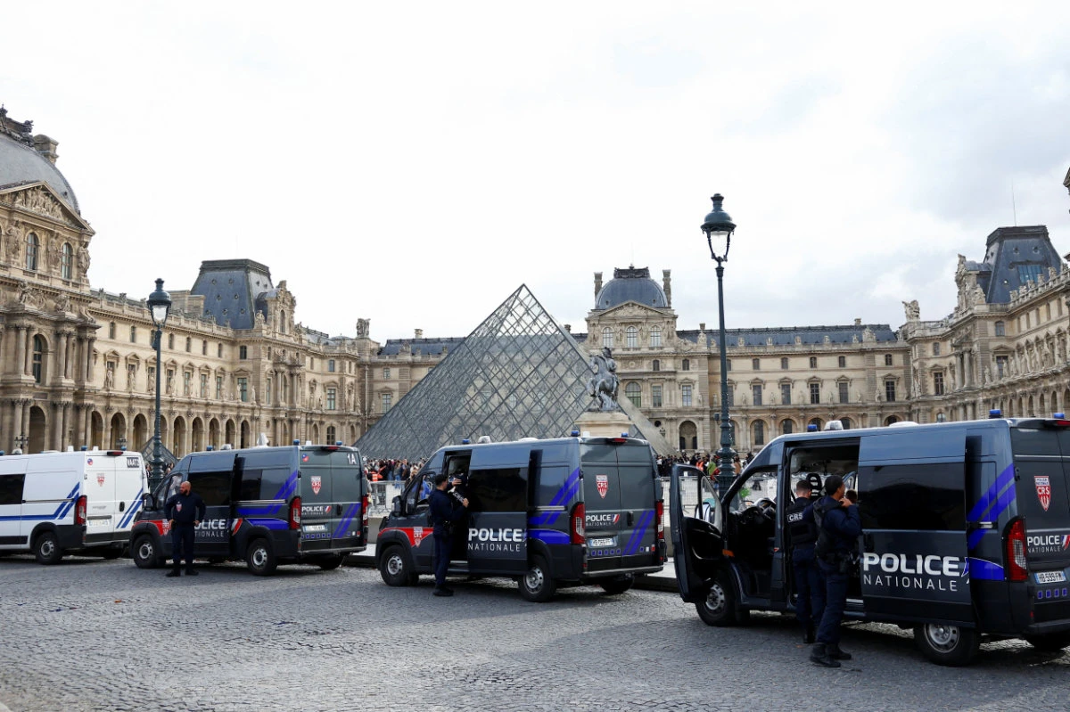 French police vans are parked near the glass Pyramid of the Louvre Museum in Paris on October 27, 2025, after police arrested suspects in the Louvre heist case. (Reuters)