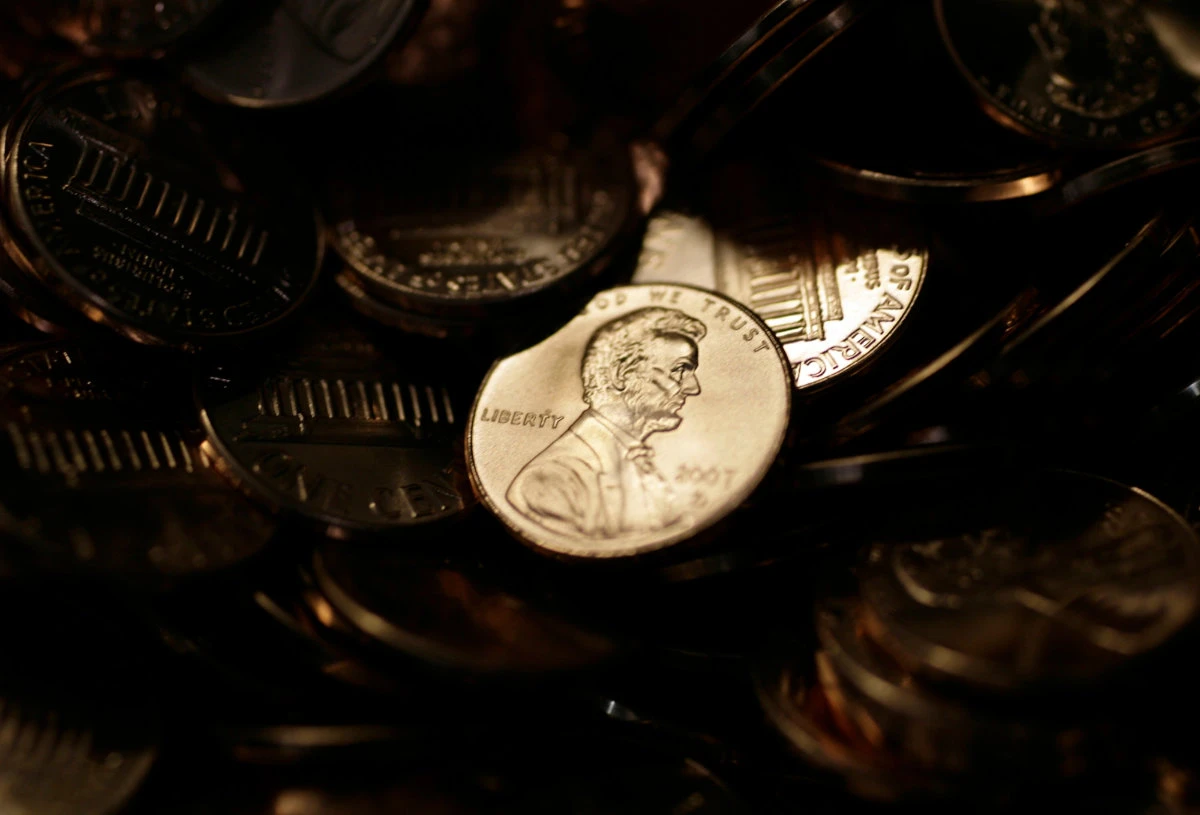 A lone penny is illuminated in a bin of completed pennies at the US Mint in Denver on Aug. 15, 2007. (AP Photo/File)