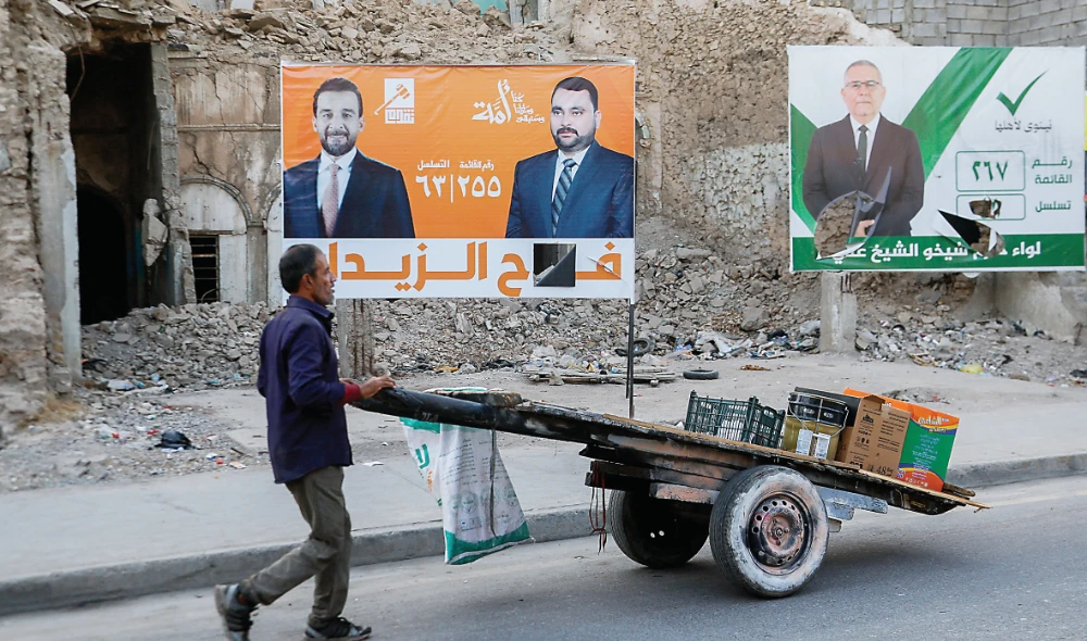 A man walks past campaign posters displayed on a street in Mosul. (Reuters)