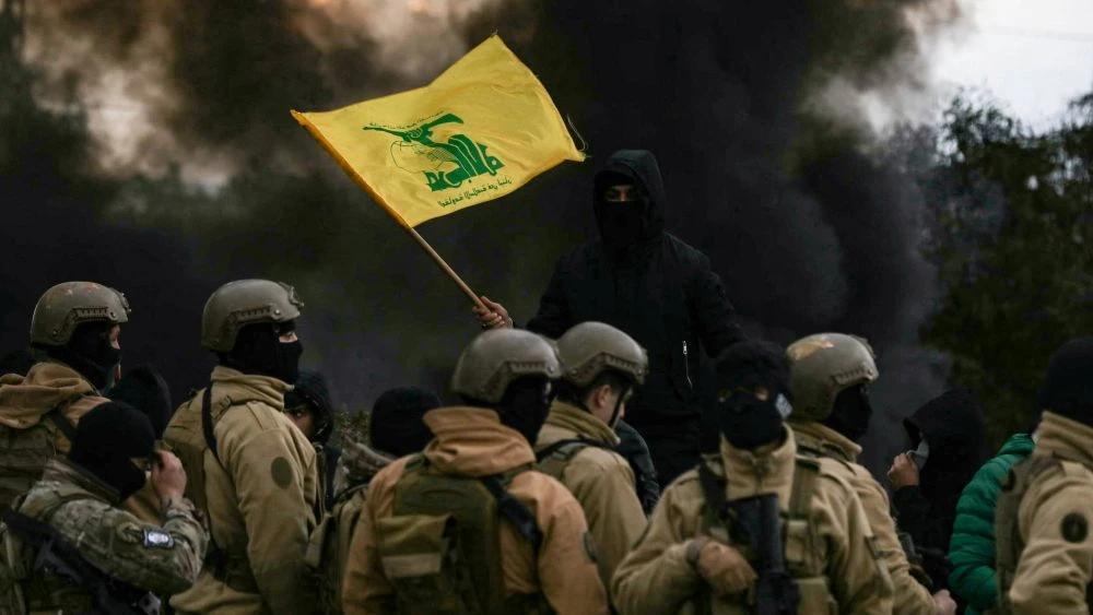 A Hezbollah supporter waves the group’s flag in front of Lebanese army troops on the road to Beirut airport, Feb. 7, 2025. (AFP)