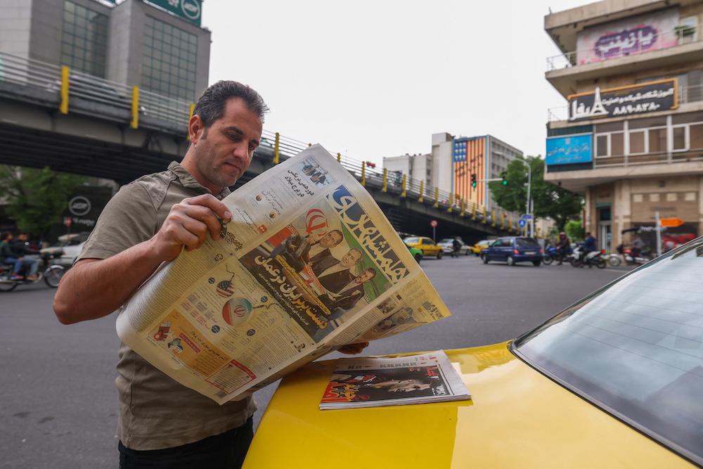 A man reads a newspaper on a Tehran street on April 12, 2025, with the front page featuring the Iran-US talks on the Iranian nuclear program set to begin in Oman on the same day. (AFP file photo)