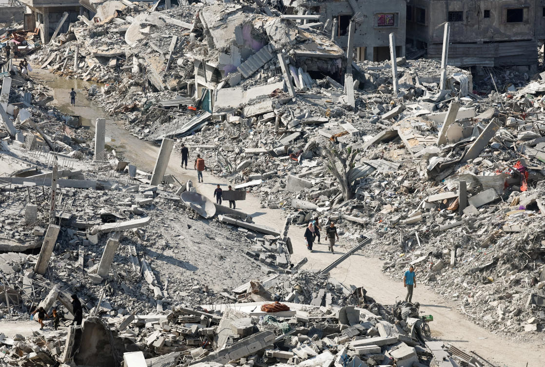 Palestinians walk past the rubble of destroyed buildings, amid a ceasefire between Israel and Hamas, in Gaza City, November 2, 2025. (Reuters)