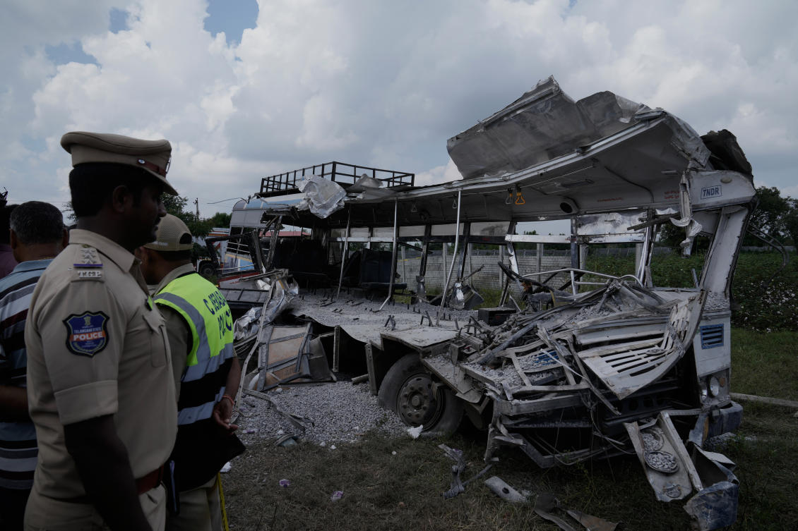 Policemen stand next to the passenger bus after a truck loaded with concrete stone chips rammed into it at Chevalla in southern state of Telangana, India on Nov. 3, 2025. (AP)