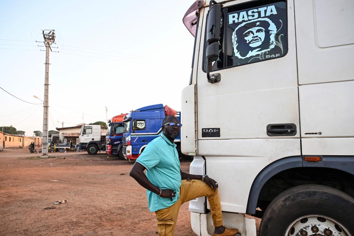 Konate Broulaye, a truck manager, poses next to a trucks parked in Boundiali where Ivorian trucks drivers refuse to go to Mali due to jihadist attacks, on October 30, 2025. (AFP)