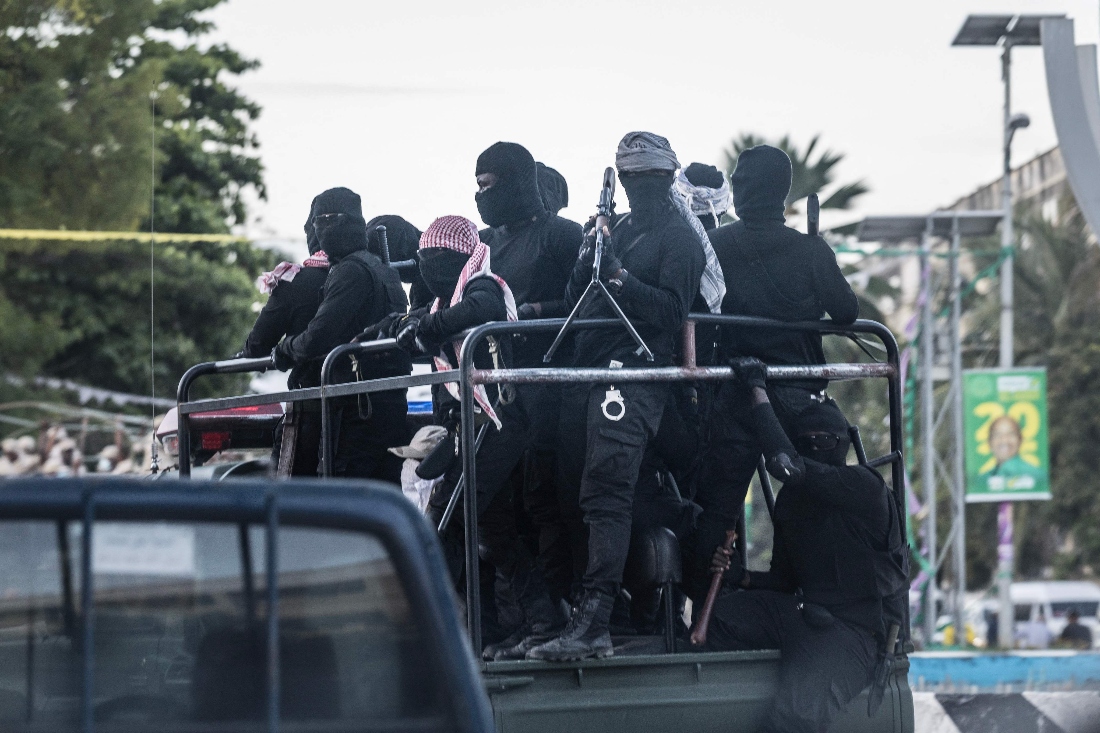 Masked armed men bearing no visible insignia or identification drive in the back of a pickup truck past electoral posters of the ruling Chama Cha Mapinduzi (CCM) candidate and incumbent Zanzibar President Hussein Ali Mwinyi in Stone Town. (AFP)