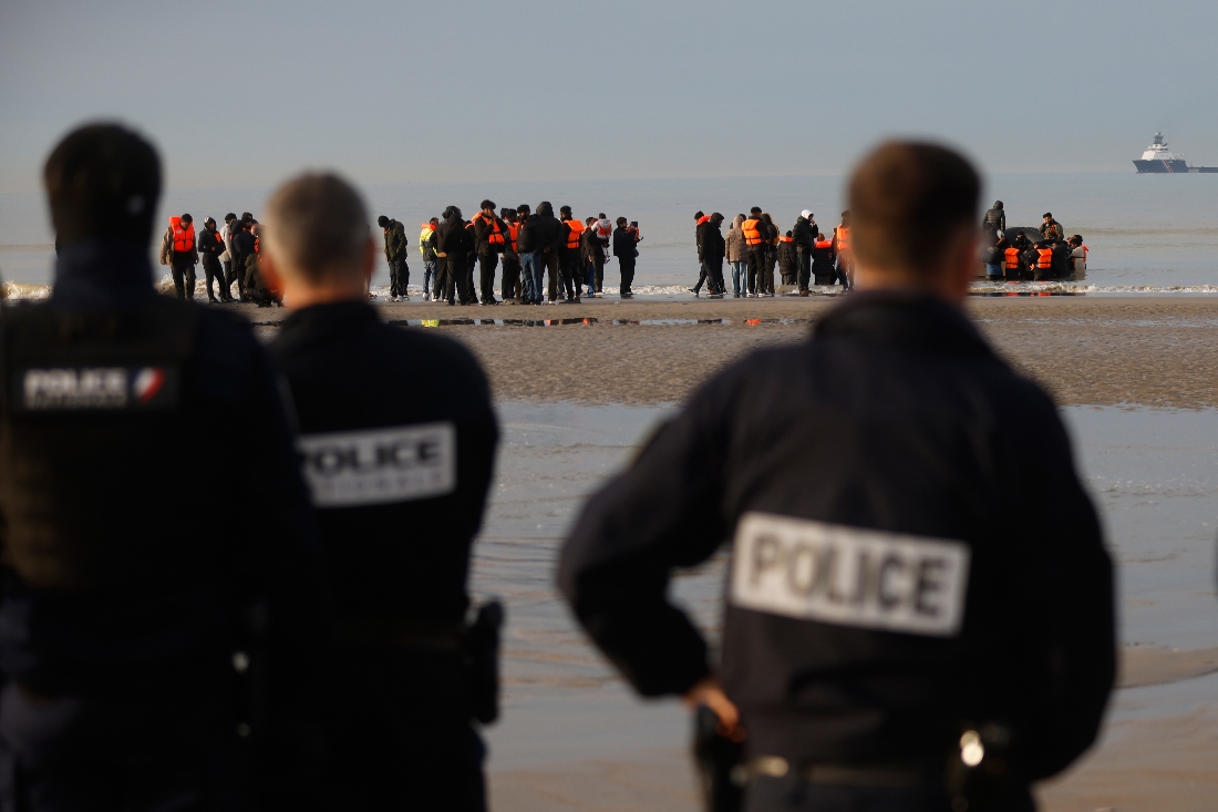 French police officers watch migrants returning to the beach after a failed attempt to reach Britain in Gravelines, northern France. (AP)