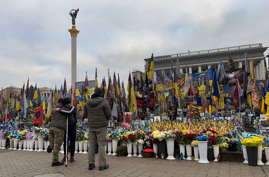 A man and wounded Ukrainian serviceman hug one another at a makeshift memorial for fallen Ukrainian and foreign soldiers, on Independence Square in Kyiv, Ukraine. (AFP)