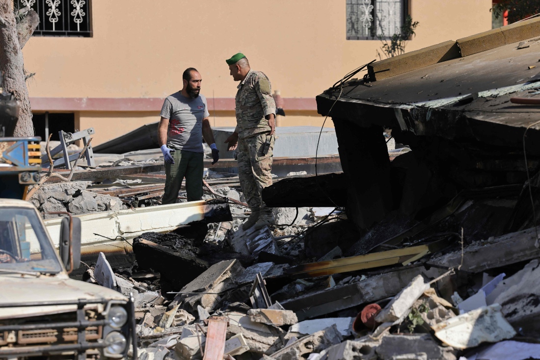 A Lebanese army soldier talks with a worker as he removes the rubble from the a site targeted overnight by an Israeli airstrike in the southern Lebanese village of Et Taybeh. (AFP)