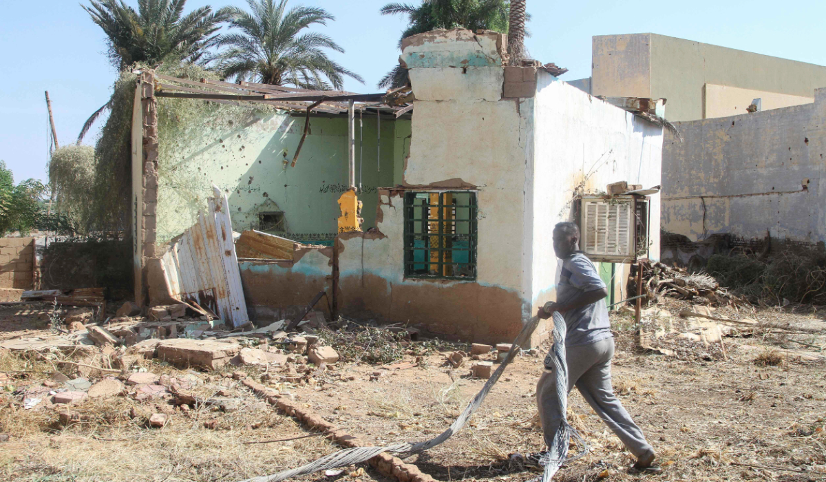 A man walks past a damaged building near the war-damaged National Theater of Omdurman, the twin-city of Sudan's capital, as Sudanese dramatists in collaboration with local authorities have launched an initiative to restore it, on November 7, 2025. (AFP)