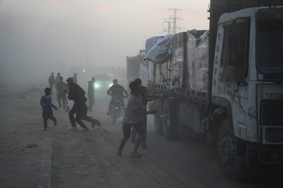 Palestinians rush toward trucks carrying aid from the World Food Programme (WFP) as they drive through Deir al-Balah in central Gaza. (AP)
