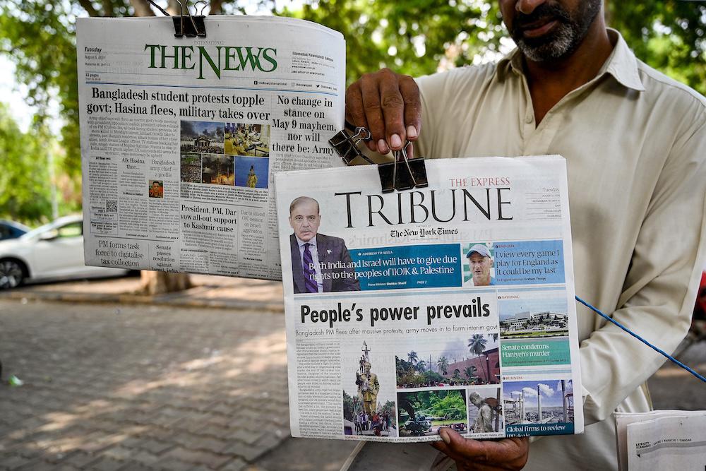 A vendor displays the front page of newspapers in Islamabad on Aug. 6, 2024, a day after Bangladesh’s Prime Minister Sheikh Hasina was ousted by anti-government protesters. (AFP)