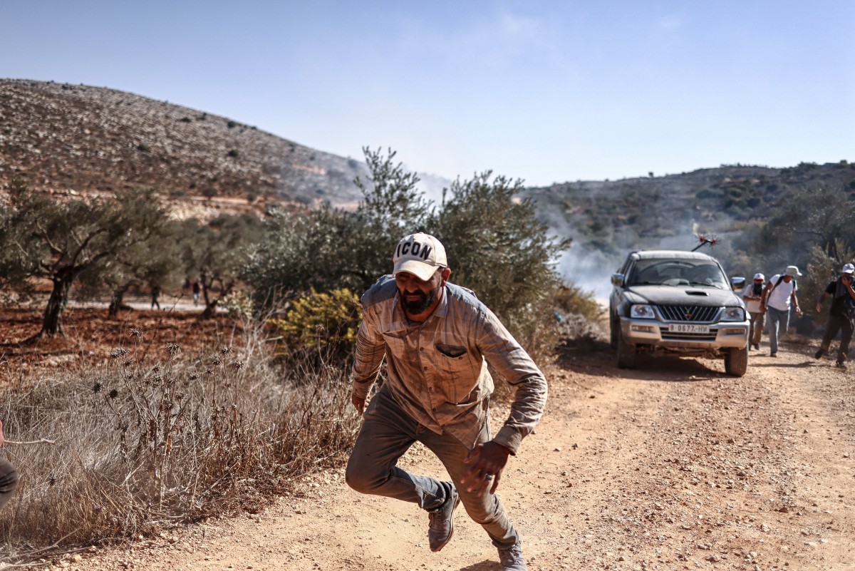 A Palestinian farmer and foreign volunteers flee as the Israeli army lobs tear gas canisters as they harvest their olive groves near the Israeli occupied Palestinian West Bank village of Turmus Ayya, near the city of Ramallah on October 28, 2025. (File/AFP)