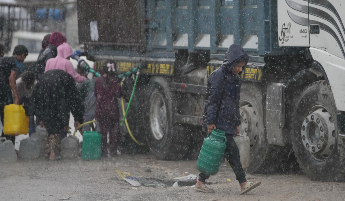 Palestinian children line up to collect water from a truck amid a rainstorm in the Sheikh Radwan neighborhood of Gaza City, Friday, Nov. 14, 2025. (AP)