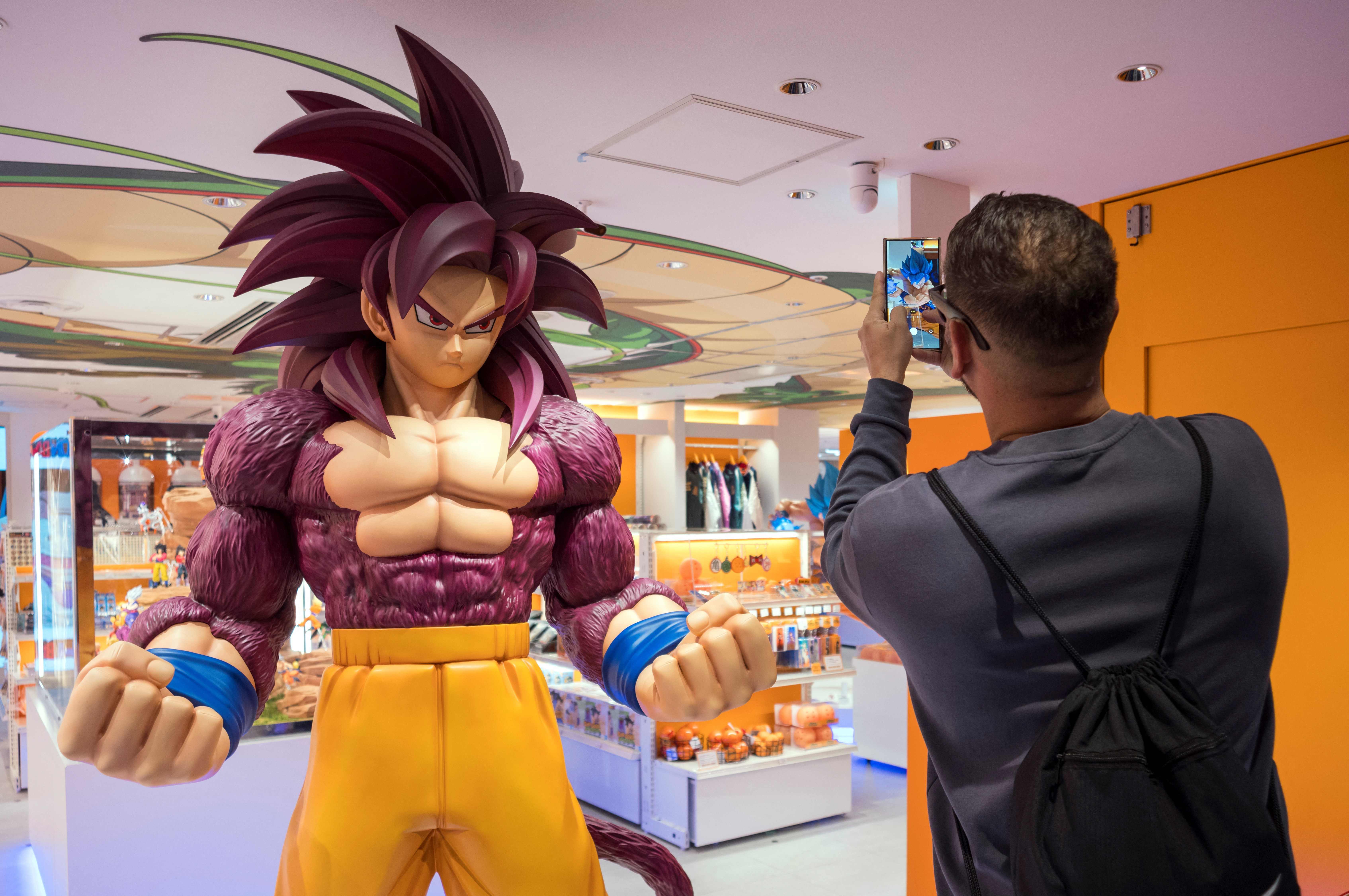 A passerby takes a photo next to a figurine of a manga character displayed in front of the Dragon Ball store at a shopping mall near Tokyo Station on Nov. 14, 2025. (AFP)