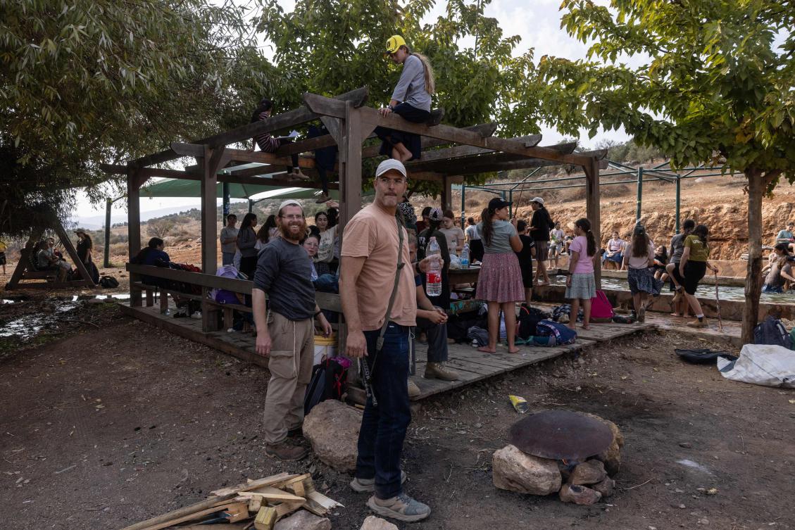 An armed settler stands next to children on a school trip in the mountains near the Jewish settlement of Elon Moreh, east of the city of Nablus in the occupied West Bank, on November 13, 2025. (Photo by Menahem Kahana / AFP)