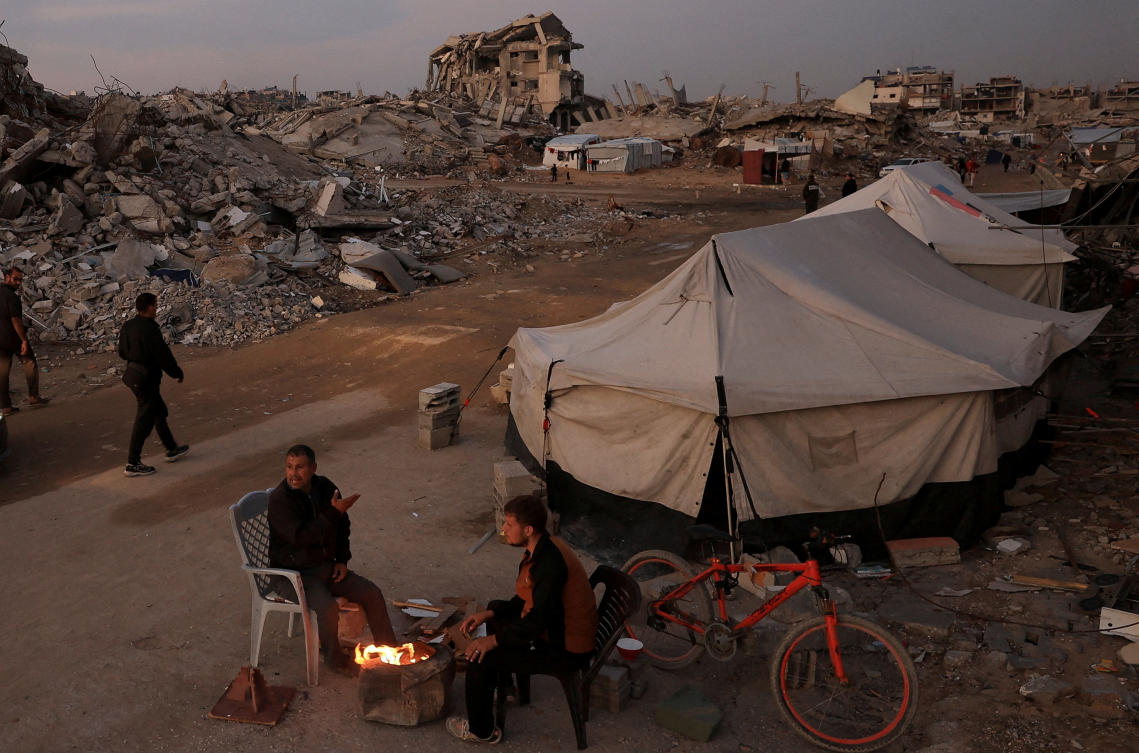 Palestinians sit next to a fire, amid a ceasefire between Israel and Hamas, in Gaza City, November 17, 2025. (Reuters)