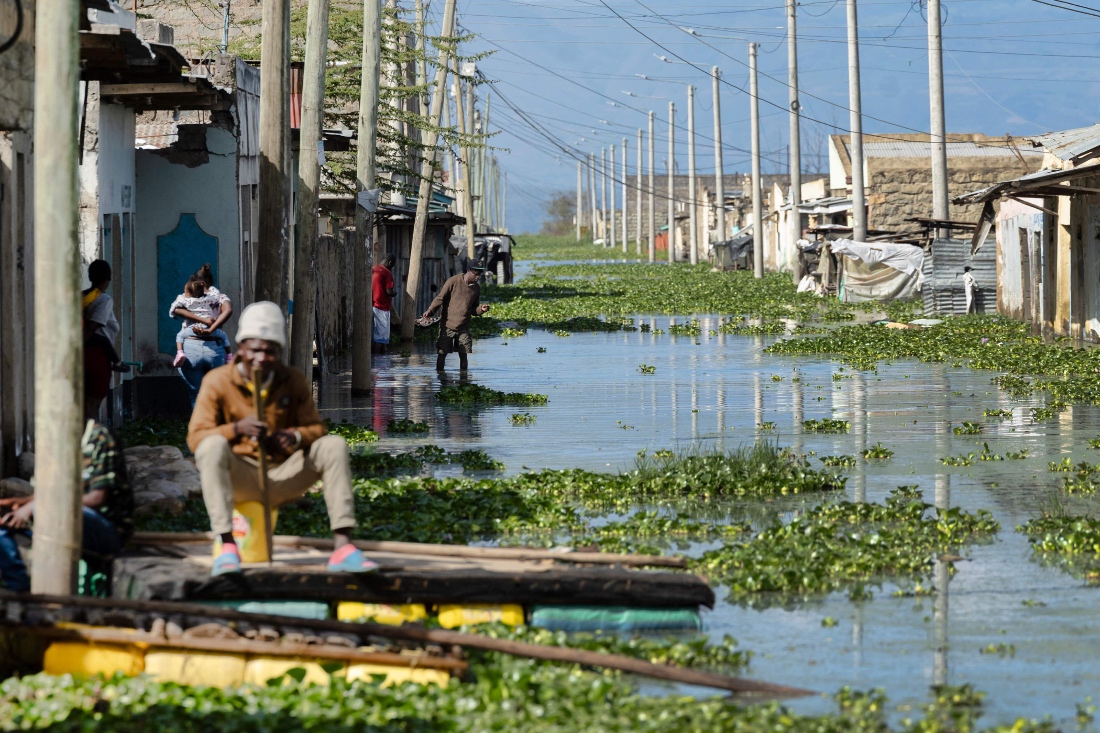 Residents wade through stagnant water over a flooded access road to their residential blocks at Kohoto estate in Naivasha, Kenya. (AFP)