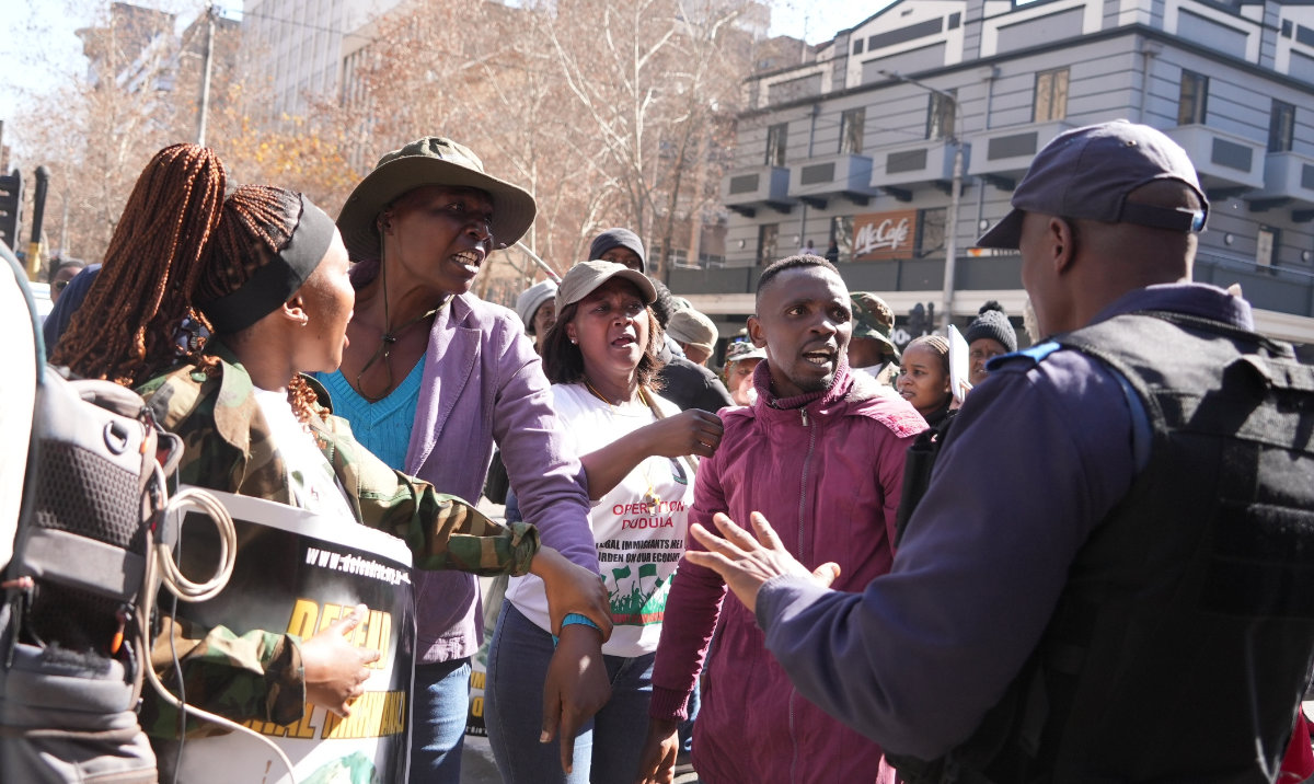 An Operation Dudula member argues with anti-xenophobia protesters and police during a march in Johannesburg. (AP/File)