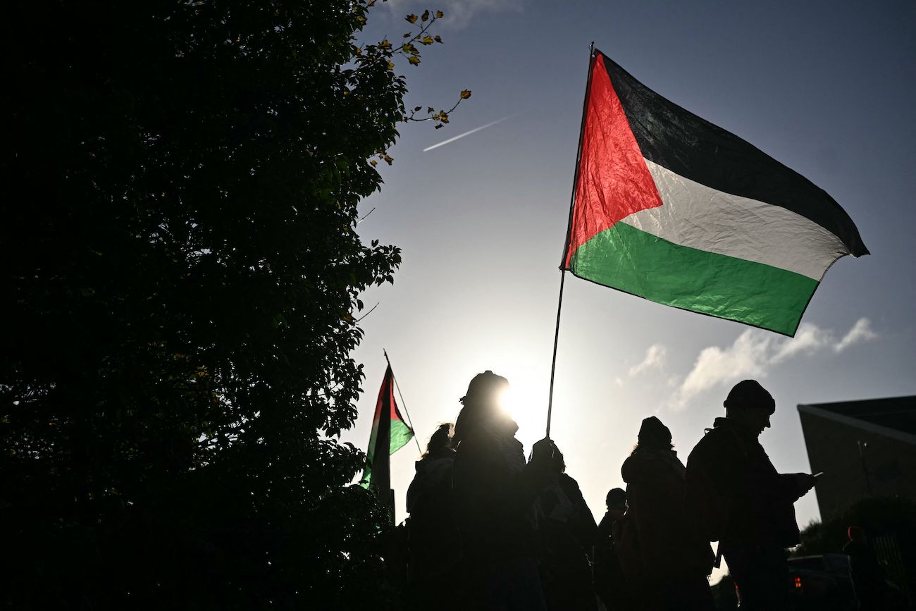 Supporters of Palestine Action activists hold placards and wave Palestinian flags outside Woolwich Crown Court in south east London on November 17, 2025. (AFP)
