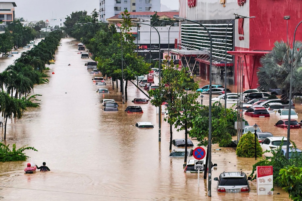 People wade through floodwaters near inundated vehicles in Nha Trang, Vietnam’s coastal province of Khanh Hoa on November 20, 2025. (AFP)