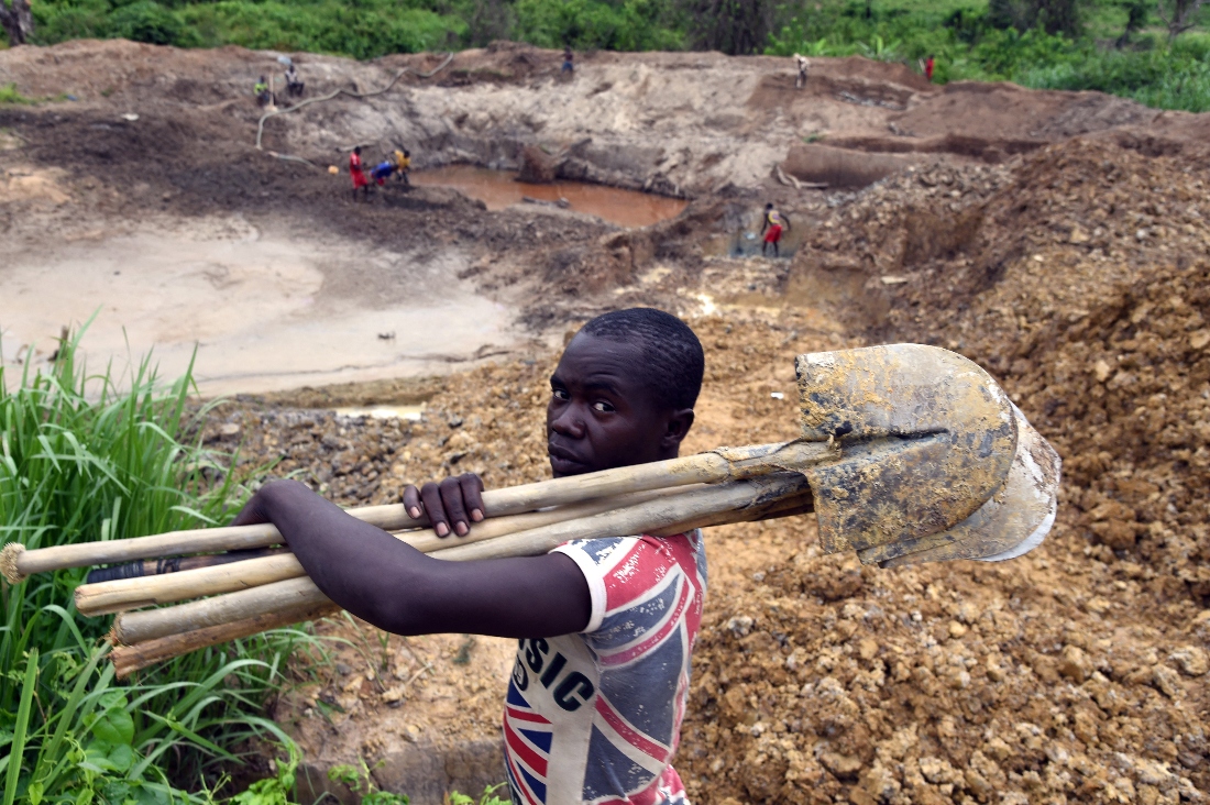A man holds a shovel as people work to find gold dust at the Gam gold mine, in Gaga, in the western part of the Central African Republic. (AFP)