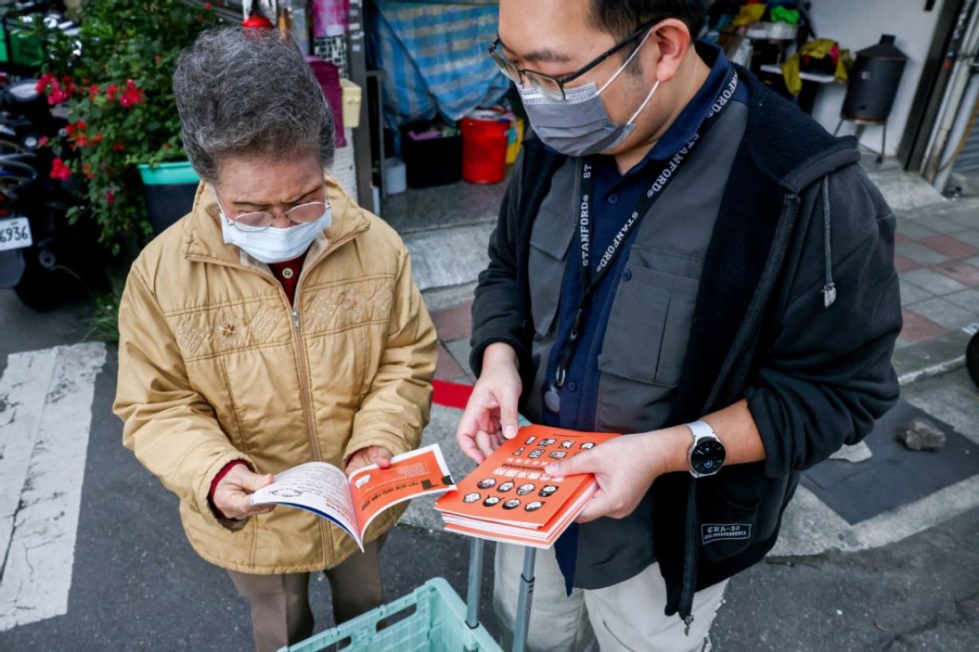 Village secretary Sean Lee giving a resident Taiwan's civil defence booklet at the Shilin district in Taipei. (AFP)