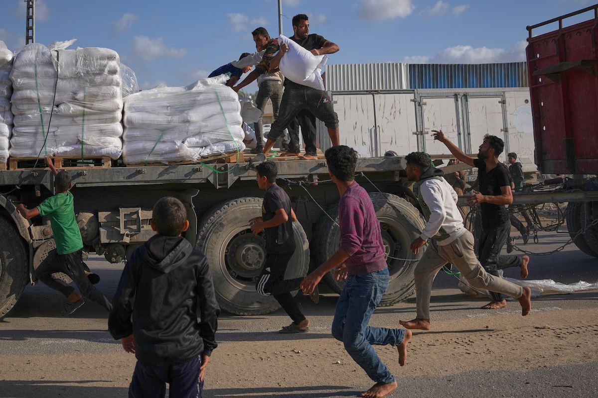 Palestinians grab sacks of flour from a moving truck carrying World Food Programme aid as it drives through Deir Al-Balah in central Gaza last weekend. (AP)
