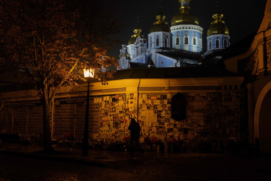 A man walks by the Wall of Remembrance of the Fallen for Ukraine, a memorial dedicated to Ukrainian soldiers during blackout hours in Kyiv, Ukraine. (AFP)