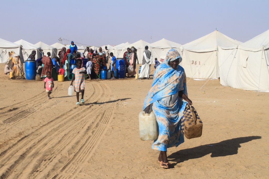 A Sudanese woman who fled El-Fasher in Darfur carries jerrycans of water at the Al-Afad camp for displaced people in the town of Al-Dabba, northern Sudan. (AFP)