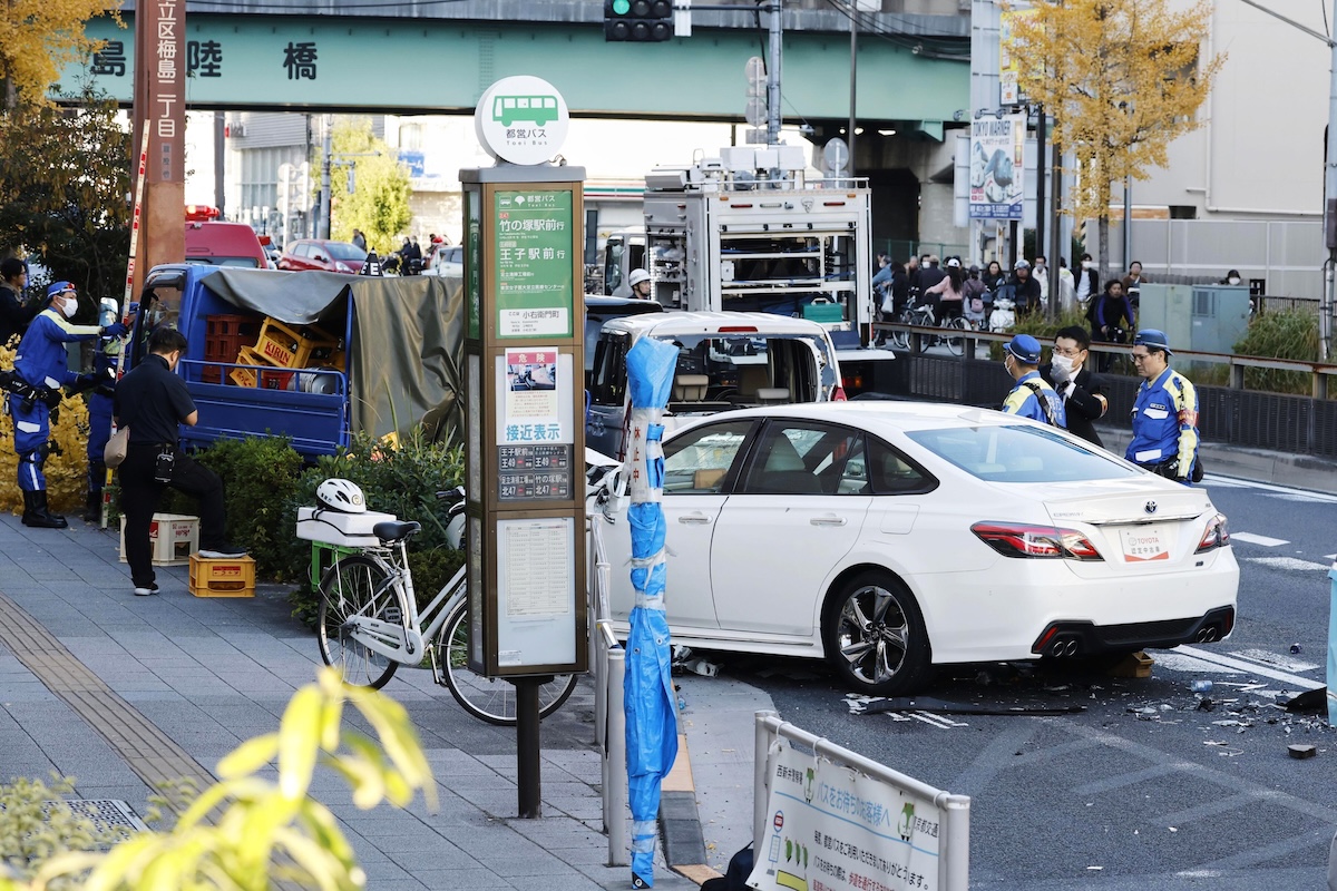 Investigators inspect the scene of a car accident injuring multiple people in Tokyo on Nov. 24, 2025. (Kyodo News via AP)