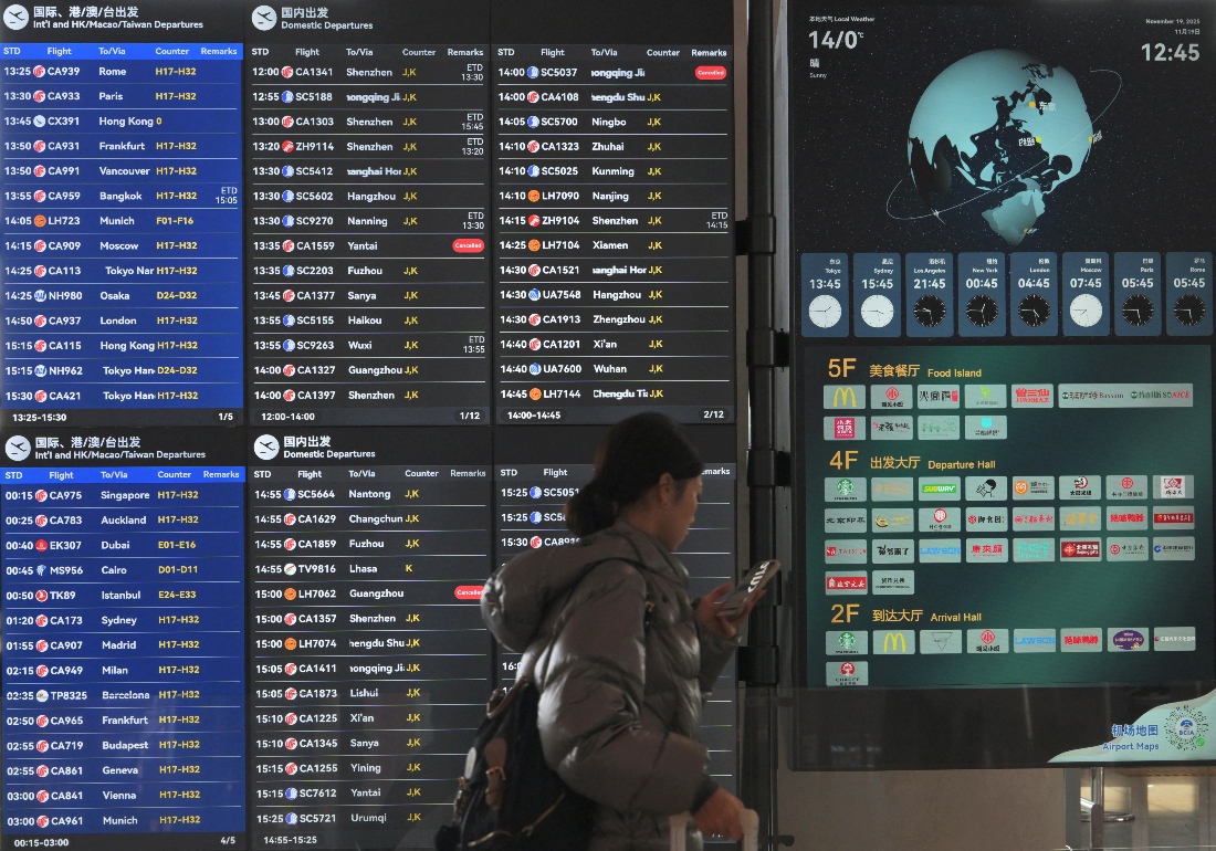 A passenger walks past a board showing international flights at the Capital international airport in Beijing, China. (AFP)