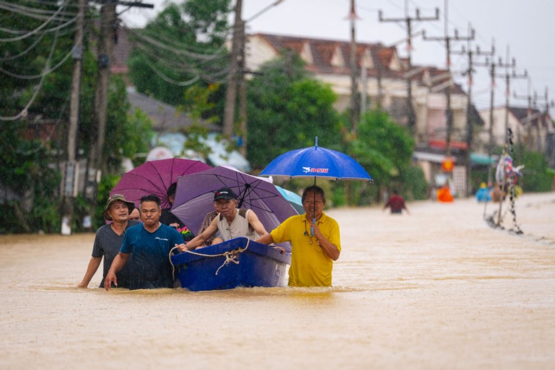 People wade through flood waters with residents being evacuated on a boat in Hat Yai in Thailand's southern Songkhla province. (AFP)