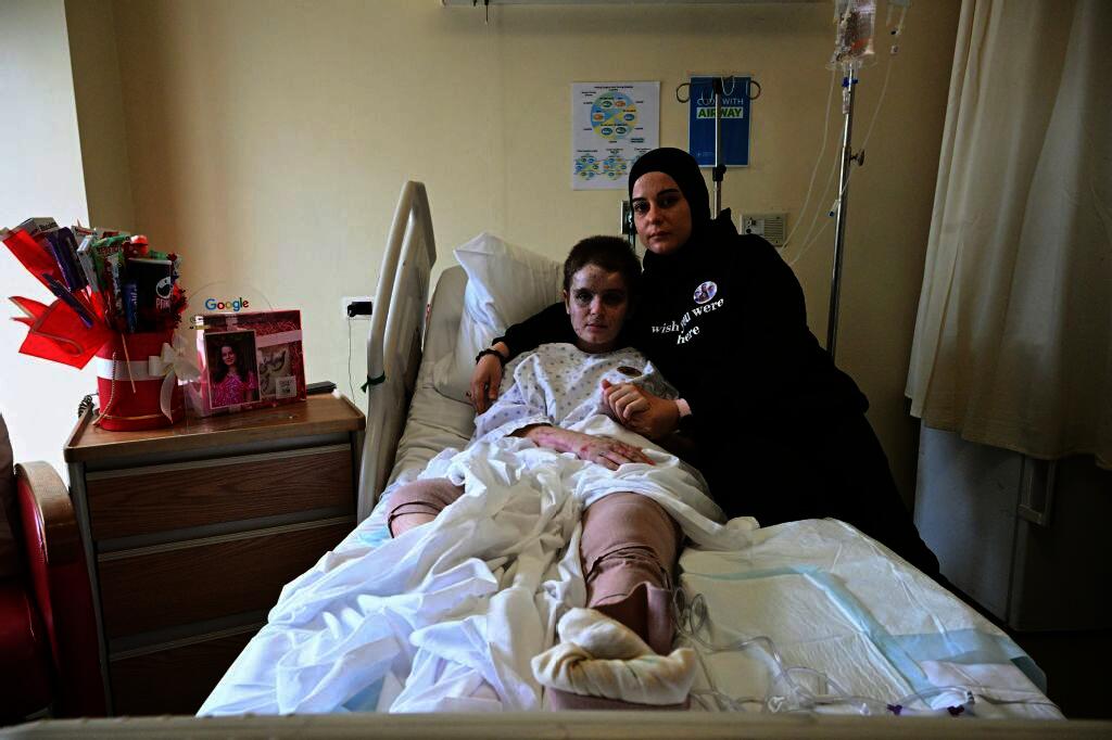 Amani Bazzi poses for a picture beside her eldest daughter Aseel at a hospital in Beirut on Nov. 25, 2025, after being gravely wounded in an Israeli military strike on Sept. 21, 2025, in the southern Lebanese town of Bint Jbeil. (AFP)