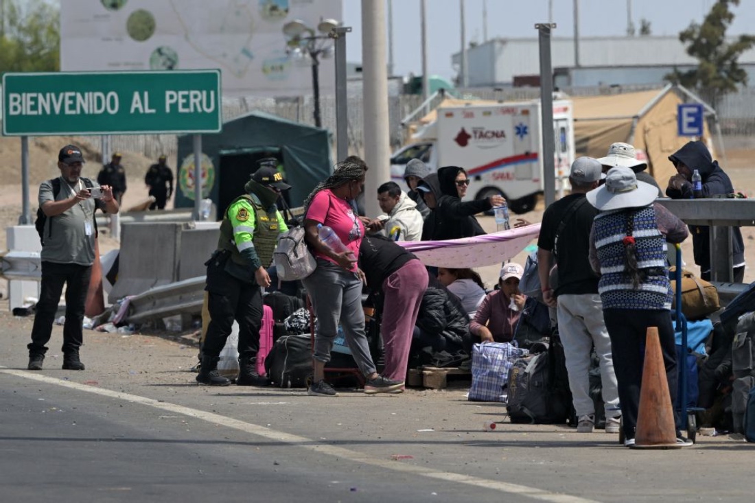 A Peruvian police officer speaks with migrants who try to enter the country, near the Cachalluta border crossing with Peru. (AFP)