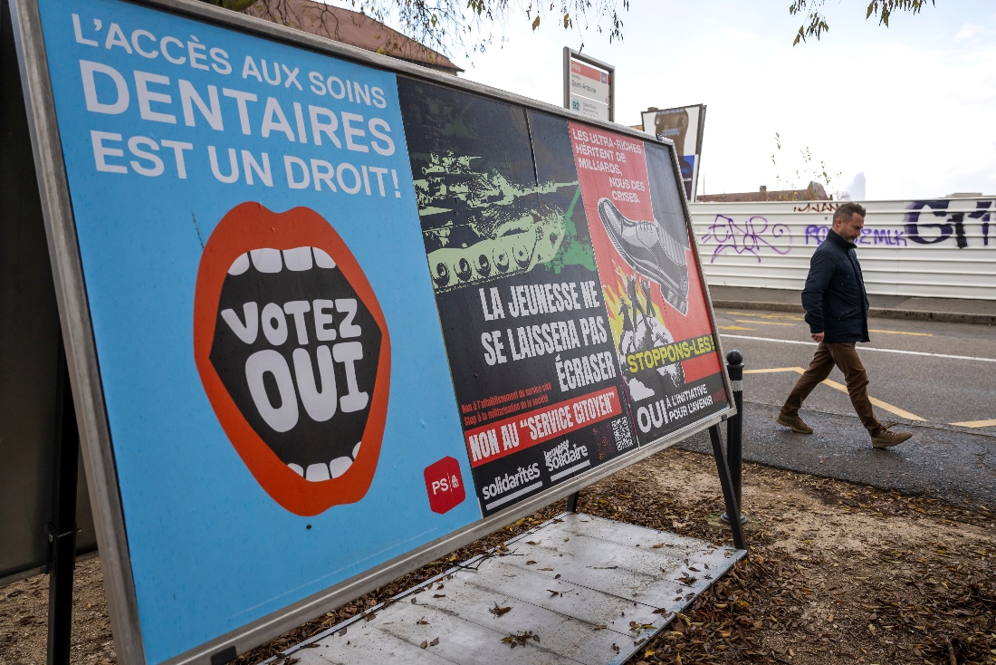 A person walks past referendum posters of political parties and associations as Swiss voters are casting ballots to decide whether women, like men, must do national service in Geneva, Switzerland. (AP)