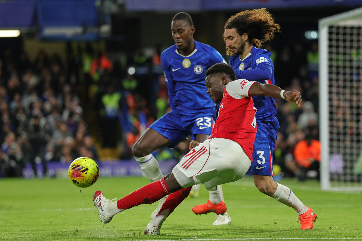 Arsenal's Bukayo Saka, centre, kicks the ball ahead of Chelsea's Marc Cucurella, right, and Chelsea's Trevoh Chalobah during the English Premier League soccer match between Chelsea and Arsenal in London, England, Sunday, Nov. 30, 2025. (AP)