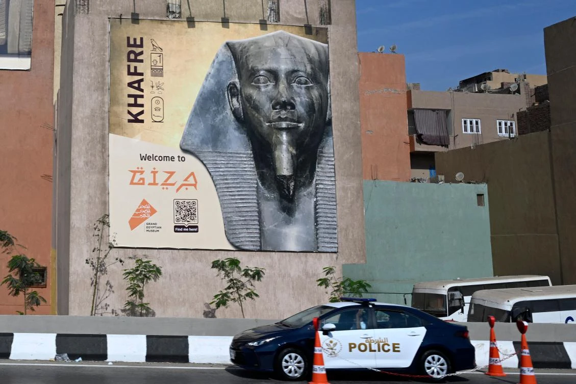 A police vehicle is stationed along the ring road close to a banner advertising the opening of the Grand Egyptian Museum (GEM), in Cairo on Nov. 1, 2025. (AFP)