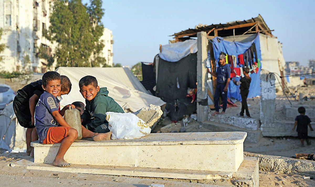 Children sit on a grave near makeshift tents in a cemetery in Khan Younis. (AP)