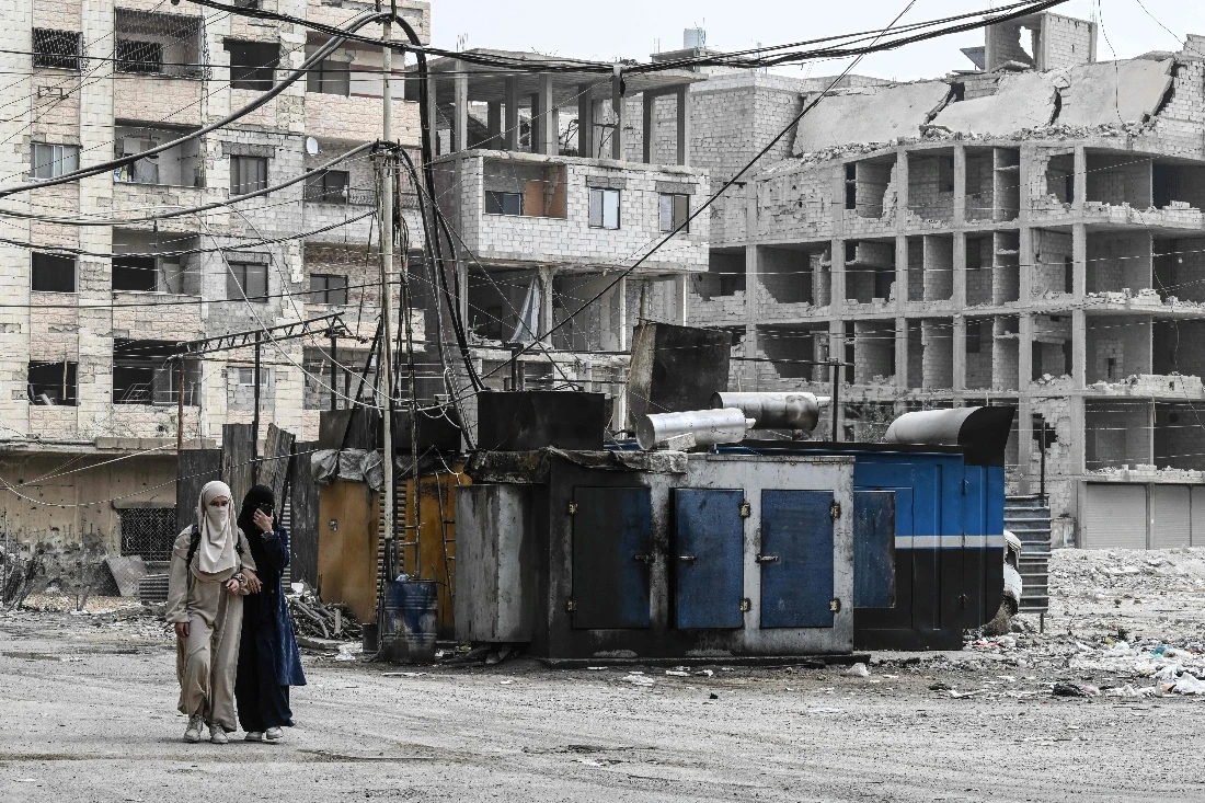 Syrian women walk past a privately owned electricity generator in the Ain Tarma area, on the eastern outskirts of the capital Damascus. (AFP)