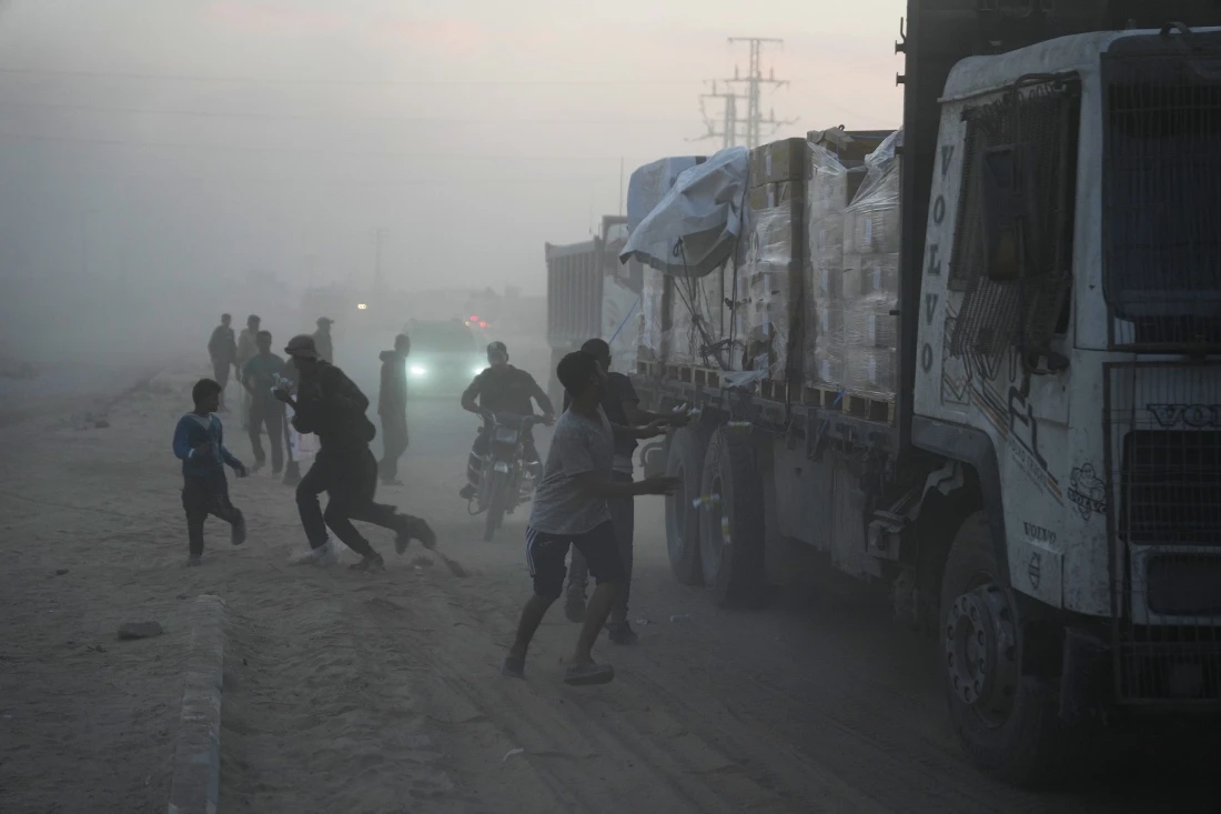 Palestinians rush toward trucks carrying aid from the World Food Programme (WFP) as they drive through Deir al-Balah in central Gaza. (AP)